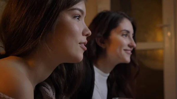 Retrato de close-up de duas jovens mulheres bonitas assistindo TV rindo alegremente em um aconchegante apartamento dentro de casa — Fotografia de Stock