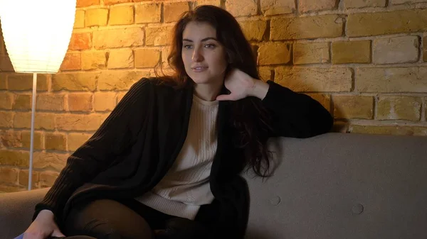 Närbild-shoot av unga attraktiva kaukasisk kvinna att vara avslappnad och titta på Tv medan schilling i soffan inomhus i en mysig lägenhet — Stockfoto