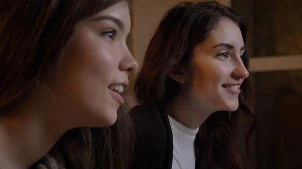 Närbild sida Visa porträtt av två unga vackra kvinnor på Tv att vara glada i en mysig lägenhet inomhus Royaltyfria Stockfoton