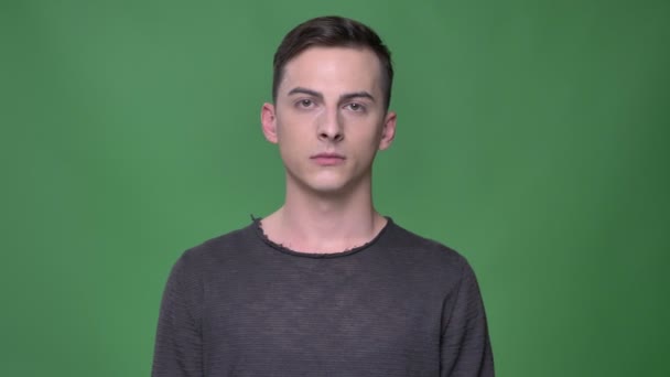 Closeup shoot of young handsome caucasian male looking straight at camera with background isolated on green — Stock Video