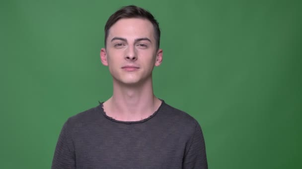 Close-up tiro de jovem bonito caucasiano masculino sorrindo feliz olhando em linha reta para a câmera com fundo isolado no verde — Vídeo de Stock