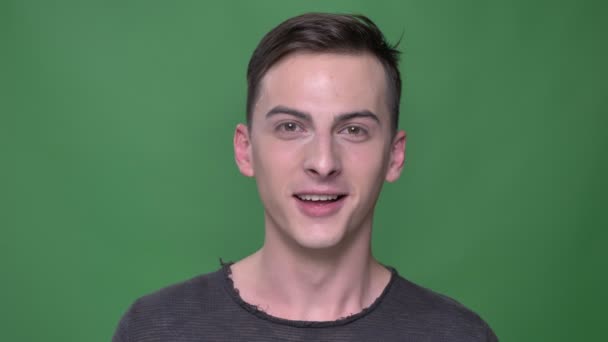 Closeup shoot of young handsome caucasian male laughing happily looking straight at camera with background isolated on green — Stock Video