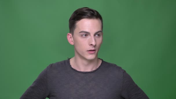 Πυροβολούν closeup των νέων όμορφος Καυκάσιος αρσενικό κυματίζοντας κεφάλι λέγοντας ότι κανένας δεν απογοητευμένοι κοιτά σε φωτογραφική μηχανή με απομονωμένα σε πράσινο φόντο — Αρχείο Βίντεο