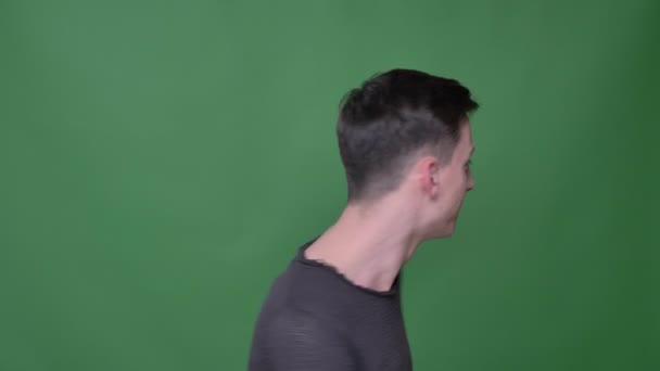 Съемки крупным планом молодого красивого белого мужчины, поворачивающегося и смеющегося, смотрящего прямо в камеру на фоне изолированного на зеленом фоне — стоковое видео