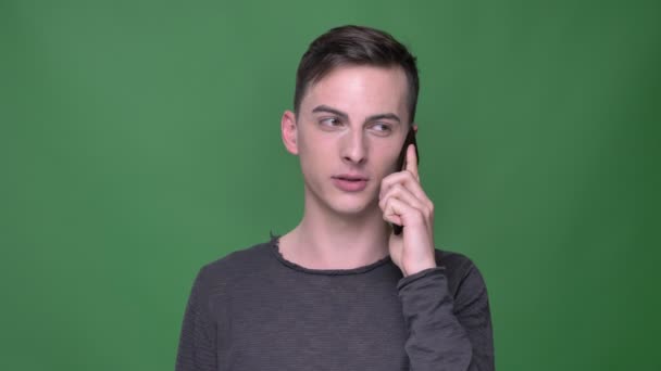 Närbild-shoot av ung stilig kaukasiska hane med ett samtal till telefonen med bakgrunden isolerad på grön — Stockvideo