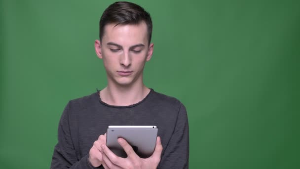 Closeup shoot of young handsome caucasian male using the tablet with blue screen with background isolated on green — Stock Video