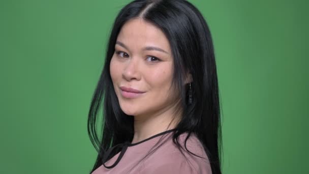 Closeup shoot of young attractive asian female turning smiling cheerfully and looking straight at camera with background isolated on green — Stock Video