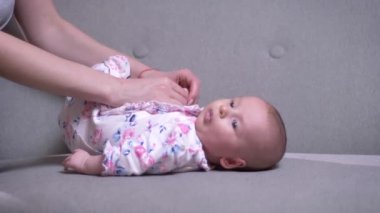 Yakın çekim portre sevimli yeni doğan kızı kanepe oturma odasında yatan ile oynarken annesi.