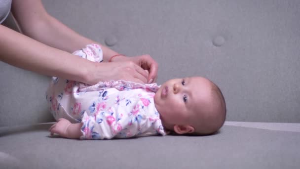 Close-up portret van moeder spelen met haar schattige pasgeboren dochter liggend op de Bank in de woonkamer. — Stockvideo