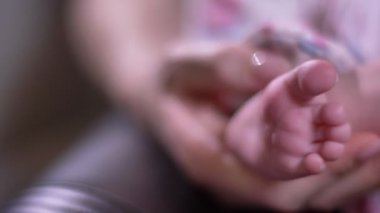 Anne bebek küçük ayağı tutan ve oturma odasında parmak yakın çekim shot.