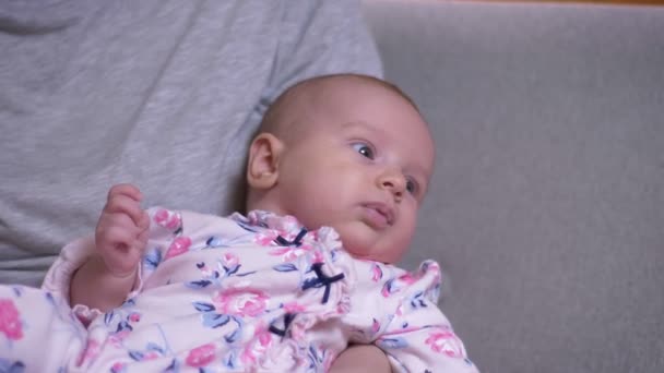 Close-up portret van schattige pasgeboren baby liggend aan moeders kant en geeuwen in de woonkamer. — Stockvideo