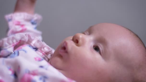 Close-up portret van leuke en mooie pasgeboren babymeisje liggend op de Bank en maak gezichten in de woonkamer. — Stockvideo