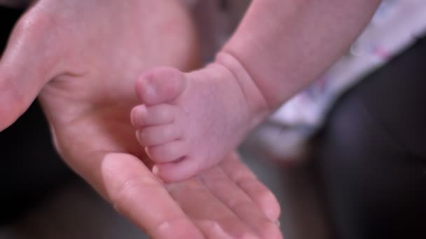 Yakın çekim mothertouching bebek küçük ayak ve oturma odasında parmak. — Stok video