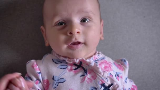 Retrato de cerca de una chica bonita recién nacida mirando a la cámara alegremente con una linda sonrisa y gritando . — Vídeos de Stock