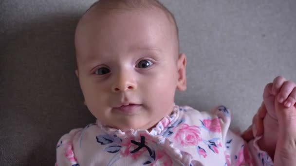 Close-up portrait of pretty newborn girl watching into camera playfully and joyfully. — Stock Video