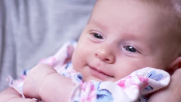 Portrait of young cute newborn daughter lies on mother s hands and watches joyfully and prettily in the living room. — Stock Video