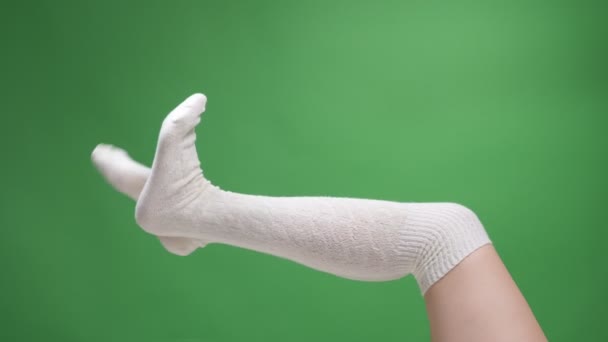 Närbild skjuta av kvinnliga tonåriga ben i söta vita strumpor lyckligt rör sig med bakrund isolerad på grön — Stockvideo