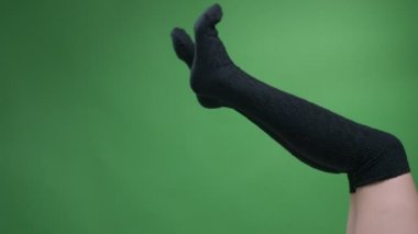 Sevimli siyah örme çoraplarda kadın genç bacakların çekim çekimi yeşil üzerinde izole artalanları ile hareketli oyuncak