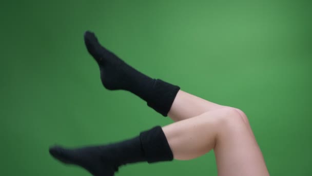 特写镜头侧视图拍摄的少女腿在可爱的黑色短针织袜子愉快地移动与背景被隔绝在绿色. — 图库视频影像