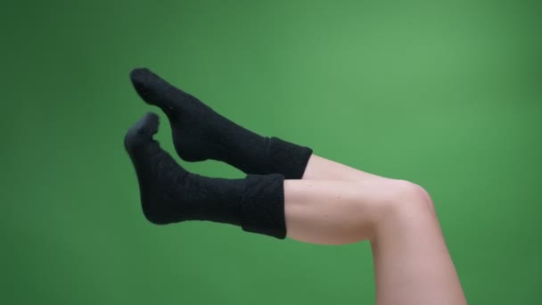 Pohled na stranu Closeup, natáčení ženských dospívajících nohou v rozkošných krátkých černých pletených ponožkách šťastně se stěrajícími na zeleném — Stock video