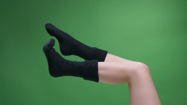 Closeup side view shoot of female teenage legs in cute short black knitted socks happily moving with backround isolated on green — Stock Video