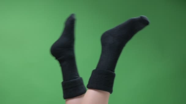 Closeup top feet shoot of female teenage legs in cute short black knitted socks playfully moving with backround isolated on green — 图库视频影像