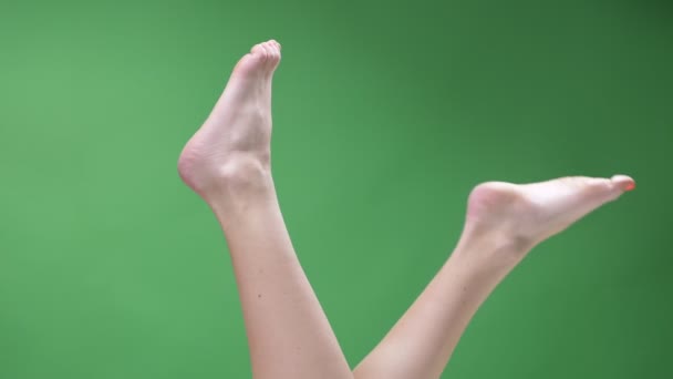 Primer plano de los pies superiores disparar de las piernas adolescentes femeninas desnuda y descalza juguetonamente en movimiento con el fondo aislado en verde — Vídeos de Stock