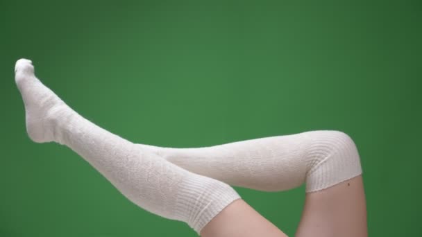 Closeup tiro de pernas adolescentes femininas em meias brancas bonitos brincando em movimento com o fundo isolado no verde — Vídeo de Stock
