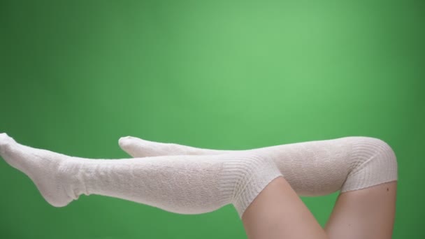 Närbild skjuta av kvinnliga ömma ben i söta vita strumpor förföriskt rör sig med bakrund isolerad på grön — Stockvideo