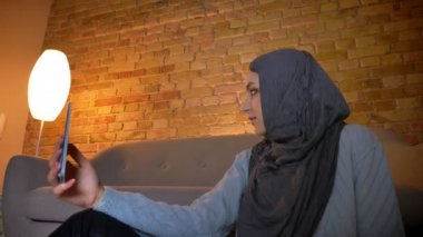 Sevimli genç çekici Müslüman kadın genç çekim alt yerde rahat evde yerde otururken telefonda selfie 'ler alarak ateş