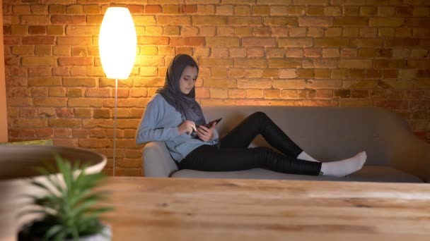 Closeup shoot of young attractive muslim female surfing web on the phone while resting laidback indoors at cozy home — Stock Video