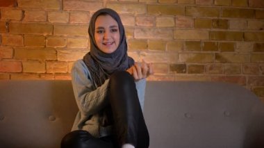 Sevimli genç çekici Müslüman kadın hijab TV 'de rahat evde kanepede kapalı otururken mutlu gülerek bir komedi izlerken çekim