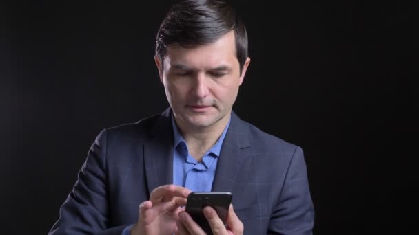 Gros plan shoot de adulte attrayant homme caucasien en utilisant le téléphone avec fond isolé sur noir — Video