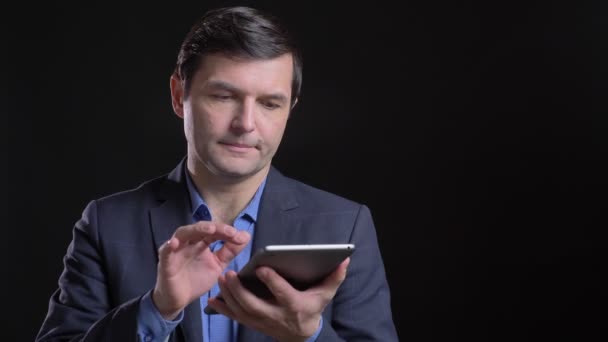 Розкладний знімок дорослого привабливого білоруського чоловіка, який використовує планшет з фоном ізольовано на чорному — стокове відео