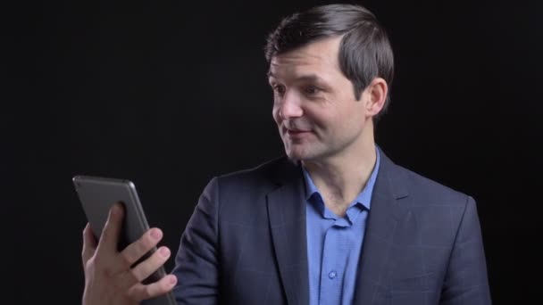 Plan rapproché de l'homme caucasien attrayant adulte ayant un appel vidéo sur la tablette avec fond isolé sur noir — Video