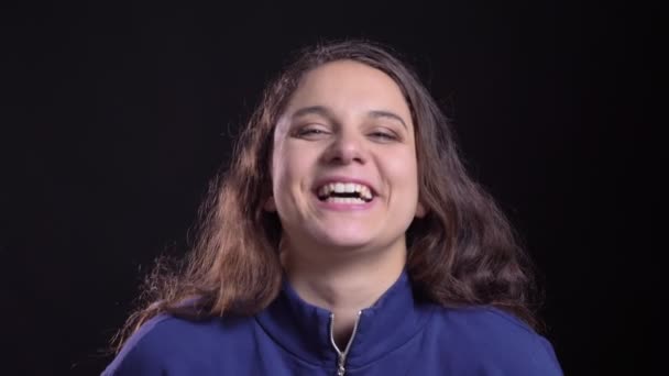 Närbild porträtt av vuxna attraktiva kaukasiska hona med lång brunett hår ser rakt på kameran och skrattar glatt — Stockvideo