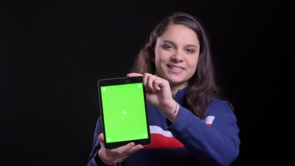 Closeup portrait of adult attractive caucasian female showing the tablet with green chroma screen to camera with background isolated on black — Stock Video