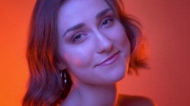 Neon kırmızı arka plan ile kameraya bakarak genç çekici beyaz kadın oyun çekim