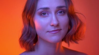 Genç çekici beyaz kadın yüz çekim ateş mutlu fotoğraf makinesi Neon kırmızı arka plan ile bakarak gülümseyen