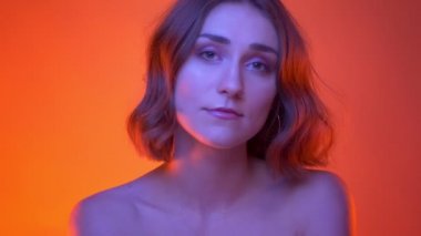 Neon kırmızı arka plan ile kameranın önünde poz delici burun ile genç çekici beyaz kadın closeup yan görünüm çekimi