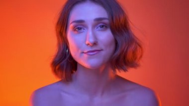 Genç kaygısız çekici beyaz kadın mutlu Neon kırmızı arka plan ile kamera bakarak gülüyor Closeup çekim