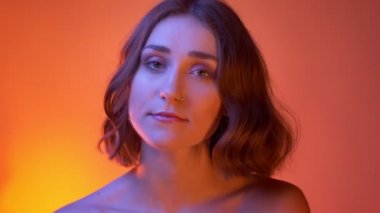 Neon kırmızı arka plan ile kamera bakarak çıplak omuzları ile genç baştan çıkarıcı beyaz kadın çekim çekim