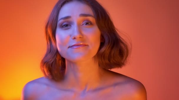 Closeup shoot of young carefree attractive caucasian female laughing cheerfully looking at camera with neon red background — Stock Video