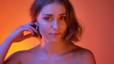 Genç baştan çıkarıcı beyaz kadın çıplak omuzlar ile kamera Neon kırmızı arka plan görünümlü saçıyla oynarken çekim çekim