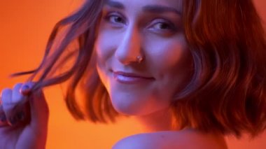 Güzel makyaj gülümseyen ve Neon kırmızı arka plan ile kameraya dönüm genç ihale beyaz kız closeup çekim