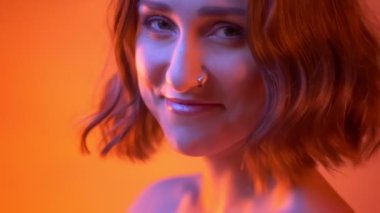 Güzel makyaj gülümseyen ve Neon kırmızı arka plan ile kameraya dönüm Genç beyaz kız closeup çekim