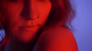 Genç çekici beyaz kadın çıplak omuz baştan çıkarıcı Neon mavi ve kırmızı arka plan ile kamera bakarak closeup çekim