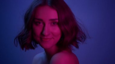 Neon mavi arka plan ile kamera dönüm genç seksi kadın closeup ateş