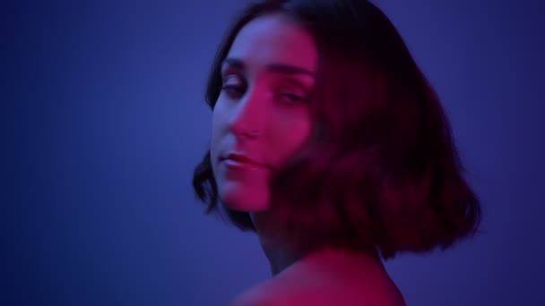 Šneka mladá sexy samice se dívá na kameru s neonovým modrým pozadím — Stock video