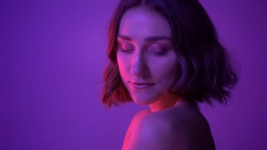 Genç çekici kadın baştan çıkarıcı Neon mor arka plan ile kameranın önünde poz closeup yan görünüm çekimi